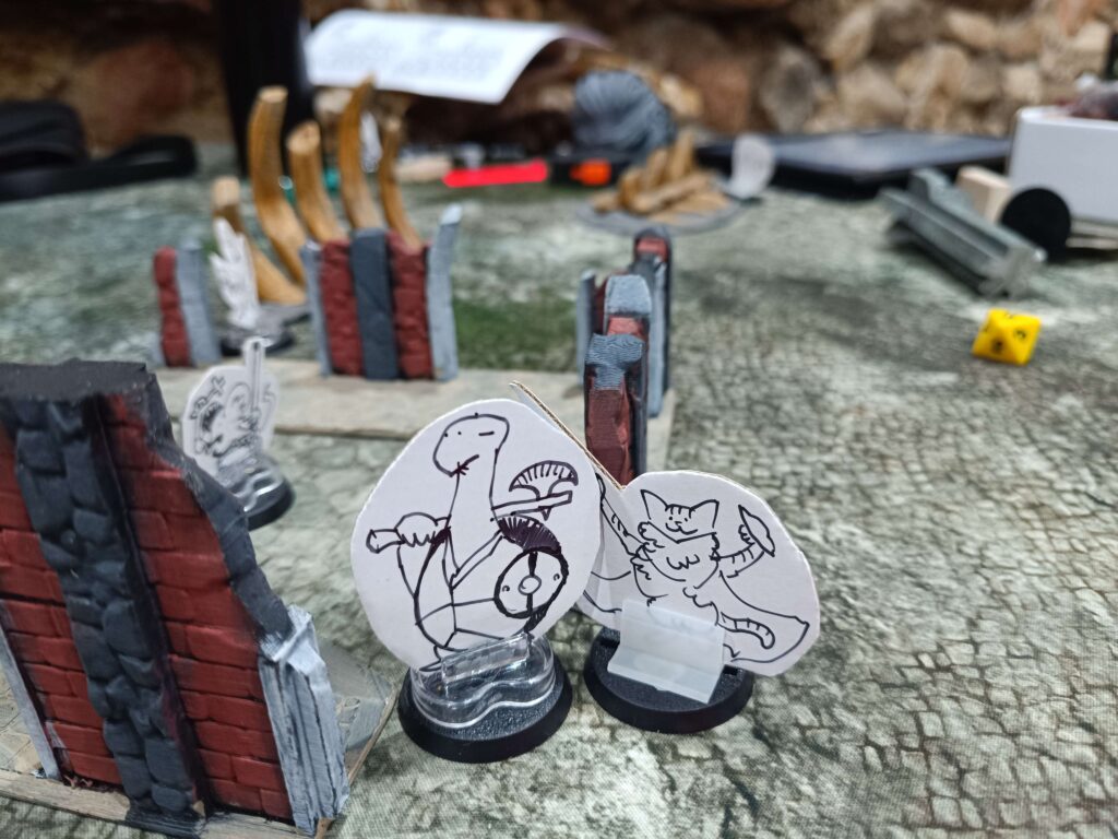 A turtle standeed faces off against a cat standee in Burrows and Badgers 2E